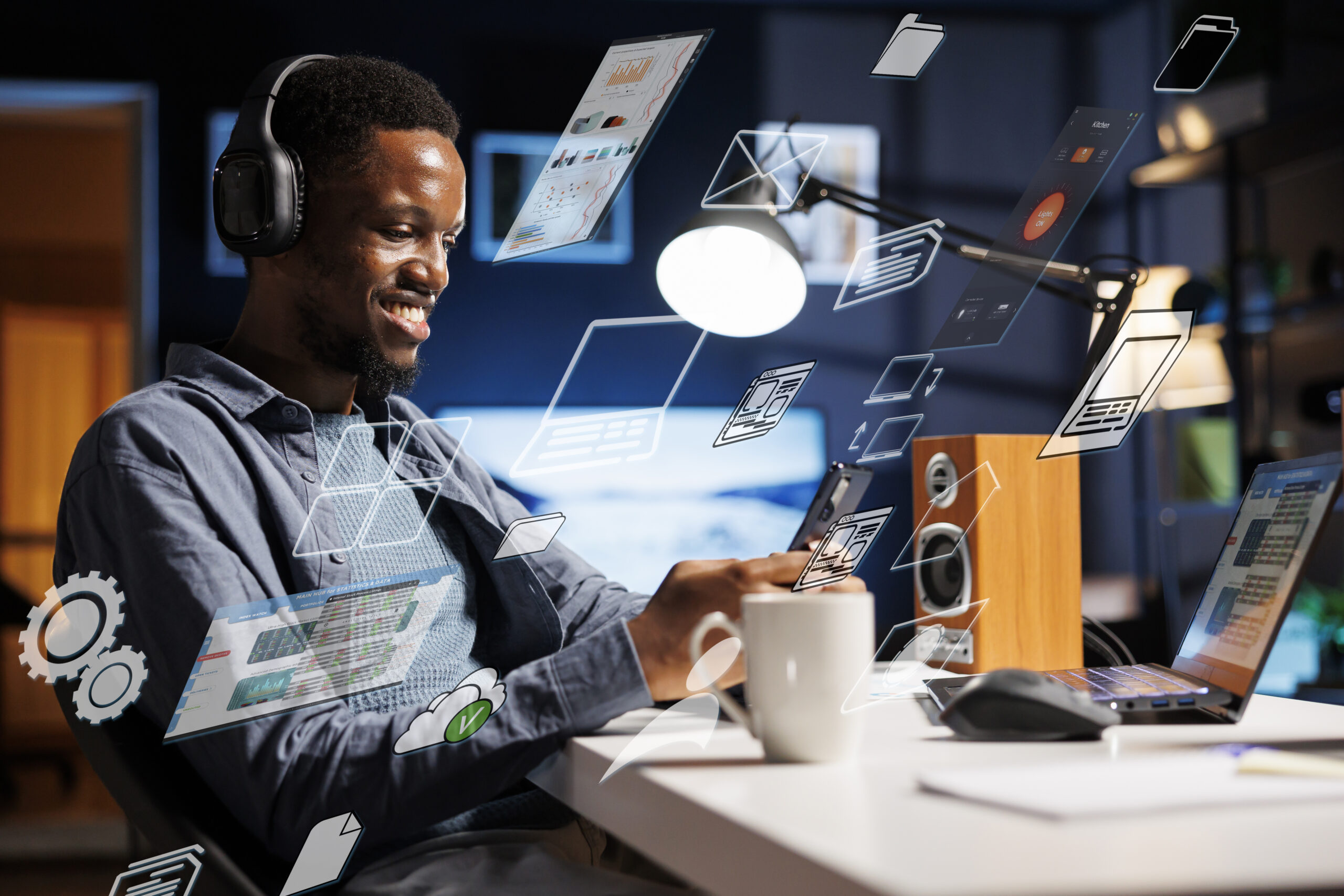 Smiling young man wearing headphones working on a laptop and smartphone at a desk, surrounded by digital icons and floating data visuals representing multitasking and digital marketing tools in a modern workspace.